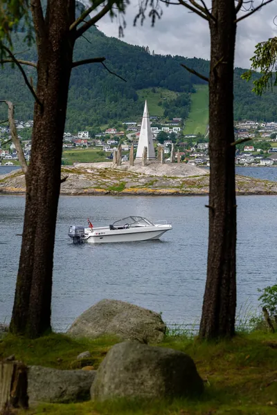 Trifoil 100GT seen through trees beside the shore